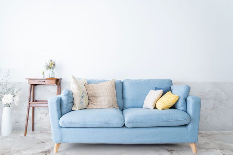 Chambre avec canapé bleu et sol et soubassement en marbre blanc