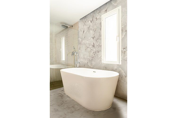 Une salle de bain avec baignoire et bac à douche avec sol et mur en marbre blanc.